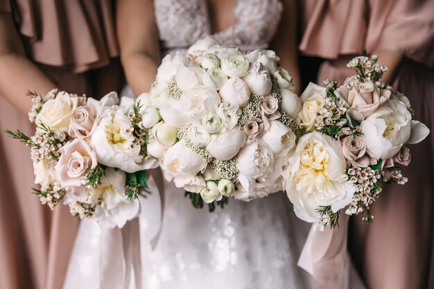 Nahaufnahme von Blumenstücken weißer Rosen, die die Braut und ihre Brautjungfern halten