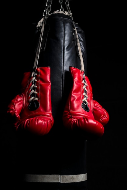 Nahaufnahme von Boxhandschuhen, die vor schwarzem Hintergrund hängen