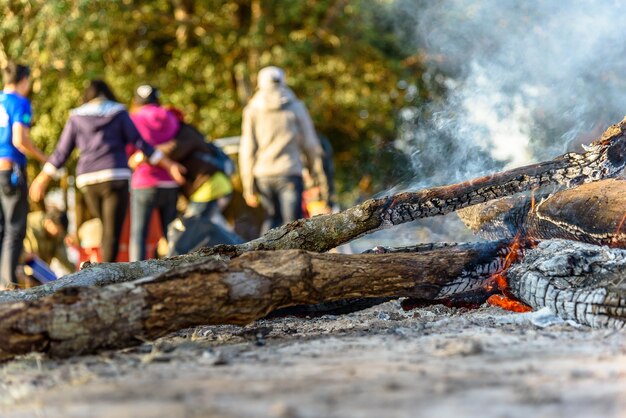 Foto nahaufnahme von brennendem holz mit menschen im hintergrund