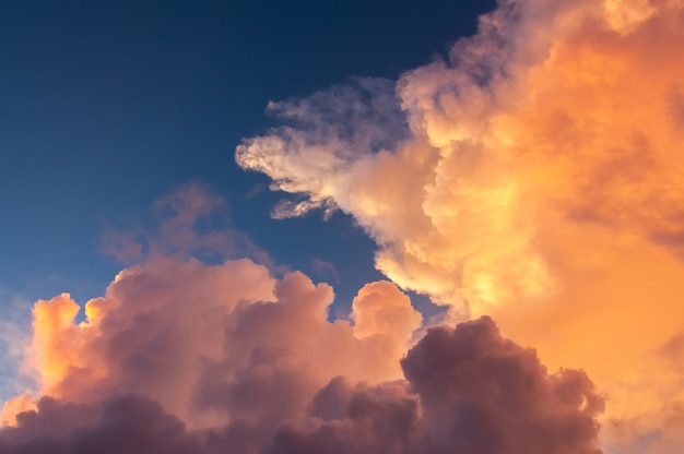 Nahaufnahme von bunten Cumulonimbus-Wolken, die durch das Abendlicht beleuchtet werden, das mit blauem Himmel kontrastiert