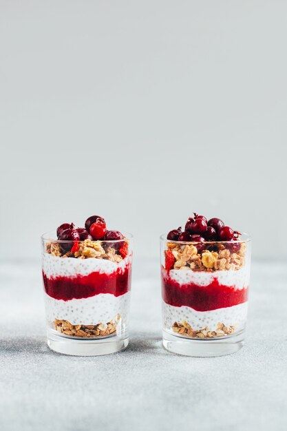 Nahaufnahme von Chia-Pudding mit Johannisbeer-Granola-Joghurt auf grauem Hintergrund