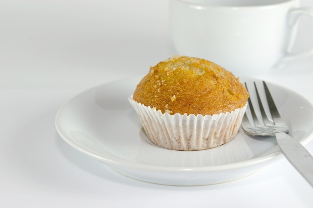 Nahaufnahme von Cupcake in Teller nach Tasse auf weißem Hintergrund