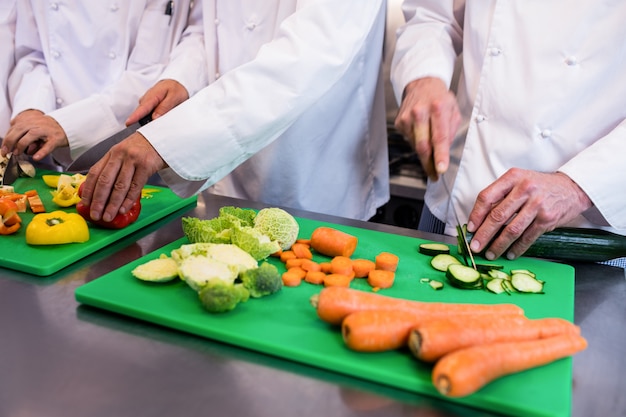 Nahaufnahme von den Chefs, die Gemüse hacken