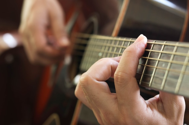 Nahaufnahme von den Fingern des Mannes, die seine Gitarre spielen