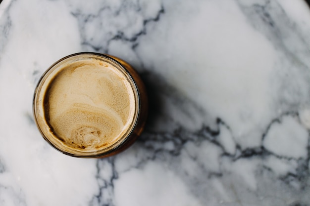 Nahaufnahme von Dirty Latte Kaffee mit Marmorstruktur auf dem Kaffee und dem Tisch.