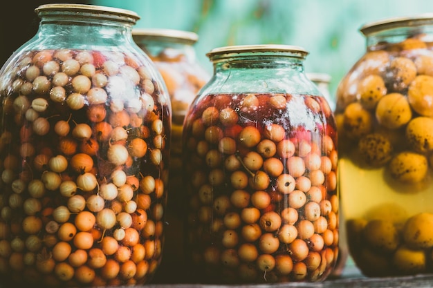 Nahaufnahme von Dosensaft mit Früchten und Beeren Versiegelte Kompottgläser auf verschwommenem Hintergrund