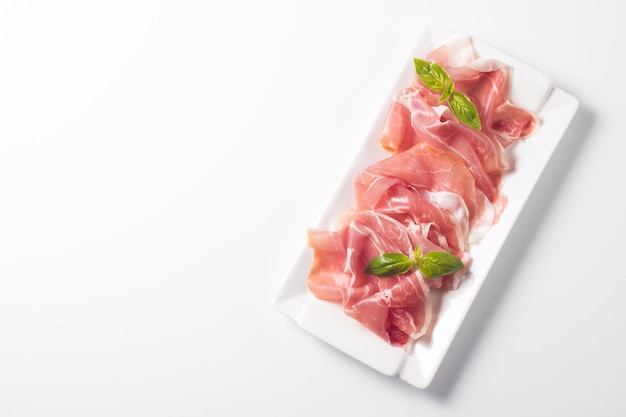 Nahaufnahme von dünnen Scheiben Prosciutto mit gemischten Oliven