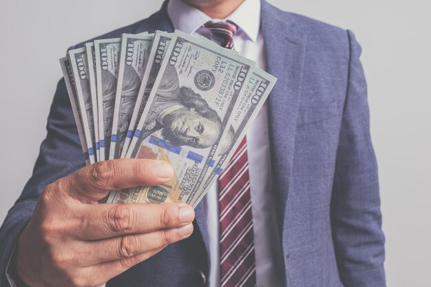 Foto nahaufnahme von einem geschäftsmann in anzug, der ein hunderthundert dollar-banknoten-geldkonzept hält
