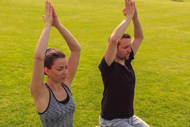 Nahaufnahme von einem gesunden Mann und einer gesunden Frau, die im sonnigen Sommerpark Yoga machen Fitness und gesunder Lebensstil