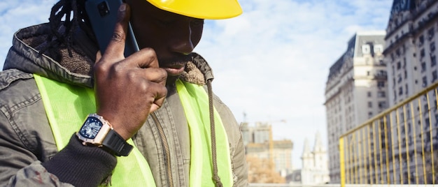 Nahaufnahme von einem schwarzen Bauingenieur auf einer Baustelle, der am Telefon spricht