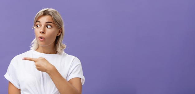 Nahaufnahme von einer faszinierten, interessierten, attraktiven, erwachsenen, blonden Frau in weißem T-Shirt, die die Lippen faltet.