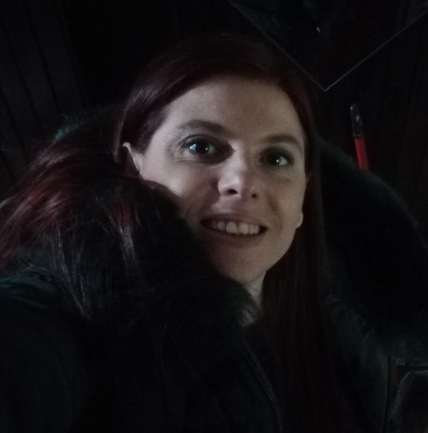 Foto nahaufnahme von einer lächelnden reifen frau in warmer kleidung im dunkelraum