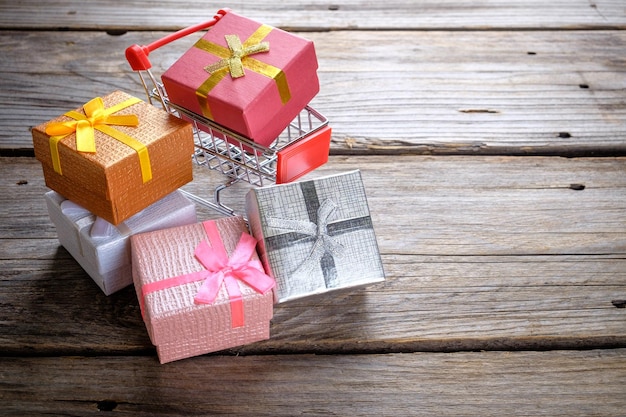 Nahaufnahme von Einkaufswagen mit Weihnachtsgeschenken auf einem Holztisch