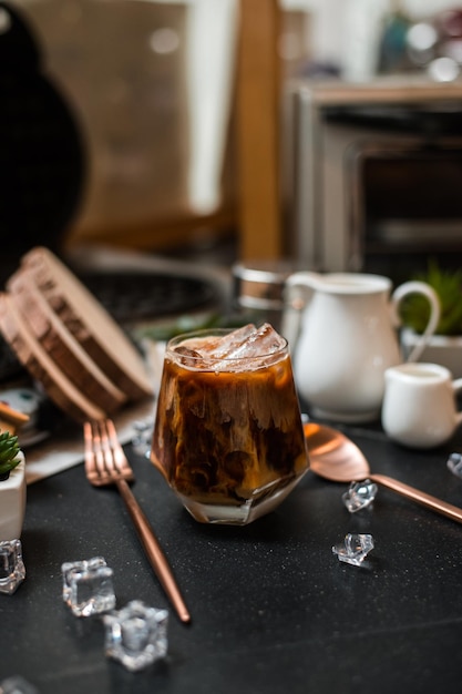 Nahaufnahme von Eiskaffee, der auf einem schwarzen Tisch im Café serviert wird