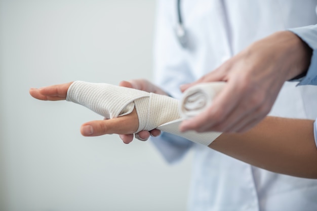 Nahaufnahme von erfahrenen Arzthänden, die Bandage fixierende Handfläche mit einem elastischen Verband machen, keine Gesichter
