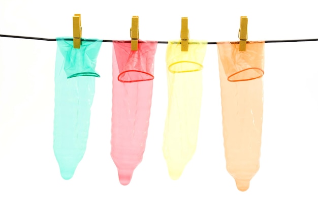 Foto nahaufnahme von farbenfrohen kondomen, die vor weißem hintergrund hängen