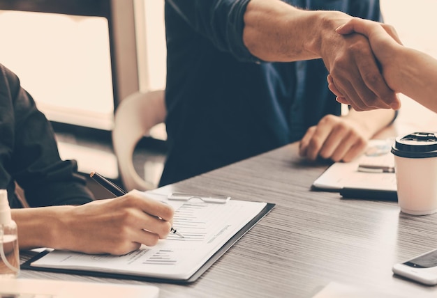 Foto nahaufnahme von finanzpartnern, die sich die hände über den schreibtisch schütteln