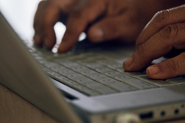 Nahaufnahme von Fingern, die auf einer silbernen Laptop-Tastatur tippen, selektiver Fokus