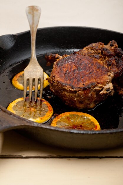 Foto nahaufnahme von fleisch mit zitronenscheiben auf der bratpfanne am tisch