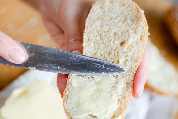 Nahaufnahme von Frauenhänden, die Butter auf eine Scheibe Brot verteilen, schnelles Essen zum Wandern oder wenn Sie nicht