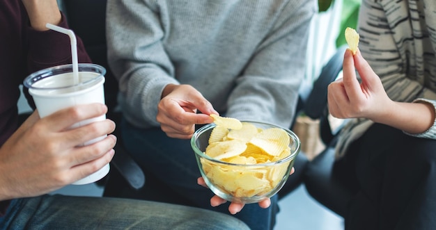 Nahaufnahme von Freunden, die zusammen Kartoffelchips trinken und essen