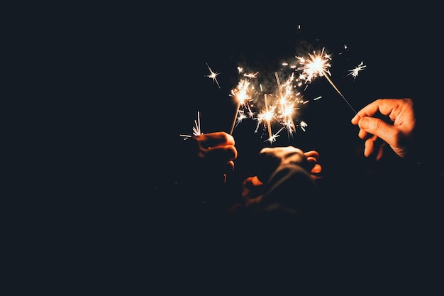 Nahaufnahme von Freunden mit leuchtenden Funkeln in der Nacht