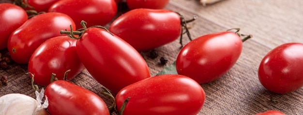 Nahaufnahme von frischen Kirschtomaten in einem Korb mit Gewürzen auf Holztischhintergrund.