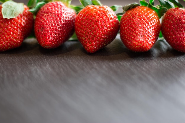Nahaufnahme von frischen roten Erdbeeren, die auf einem schwarzen Steintisch liegen