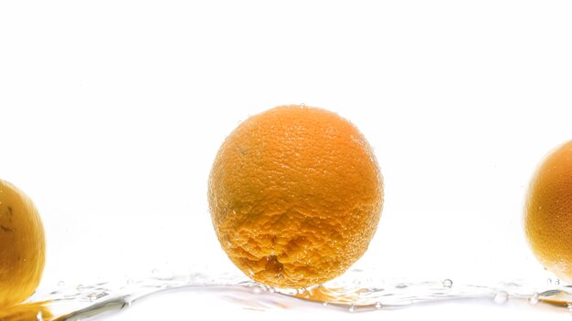 Nahaufnahme von frischen saftigen orangen, die ins wasser fallen