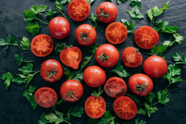 Nahaufnahme von frischen saftigen roten Tomaten und grüner Petersilie auf dunklem Hintergrund Frühlingsgemüse voller Vitamine Ernährungskonzept