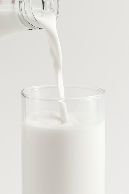 Nahaufnahme von frischer Milch in ein Glas gießen