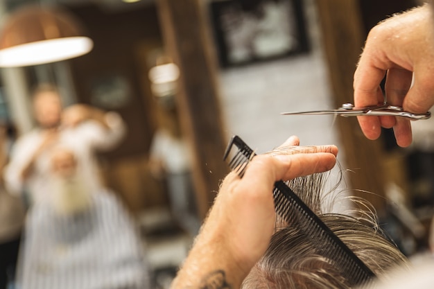 Nahaufnahme von Friseur hannds mit Schere, die stilvollen Haarschnitt macht