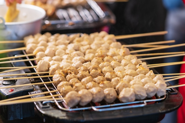 Foto nahaufnahme von gegrillten frikadellen auf bambusstöcken hintergrund, thailändischer straßenlebensmittelmarkt