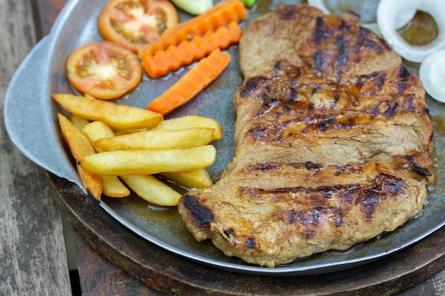 Nahaufnahme von gegrillten Schweinesteaks und Pommes Frites mit Gemüse