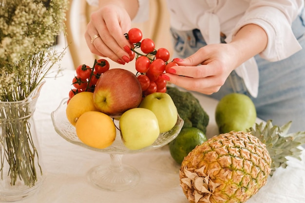 Nahaufnahme von Gemüsefrüchten auf dem Küchentisch beim KochenDie Gastgeberin hält kleine Tomaten in der Hand