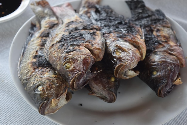Nahaufnahme von geröstetem Fisch, der auf einem Teller auf dem Tisch serviert wird