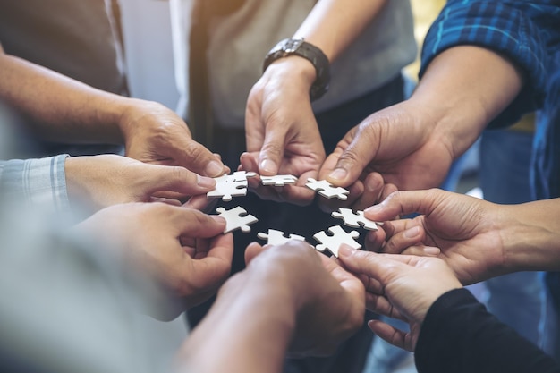 Foto nahaufnahme von geschäftsleuten, die in ihrem büro puzzle-stücke halten