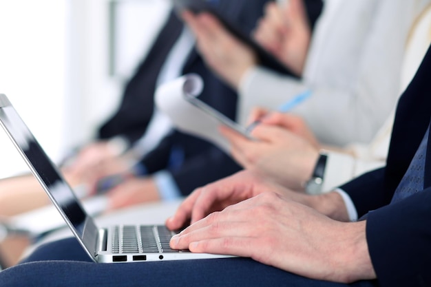 Nahaufnahme von Geschäftsmannhänden, die auf der Konferenz auf Laptop-Computer tippen.