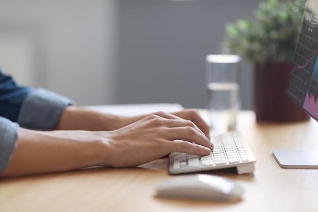 Nahaufnahme von Geschäftsmannhänden, die während der Arbeit im Büro auf der Computertastatur tippen