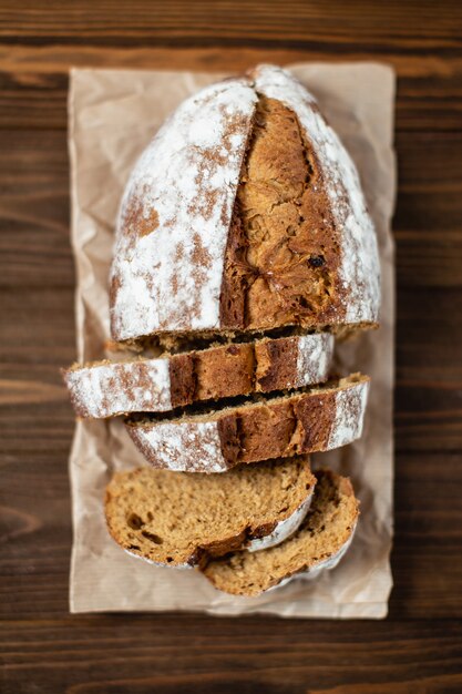 Nahaufnahme von geschnittenem gebackenem Brot. Buchweizenbrot auf Backpapier. Holzoberfläche und Hintergrund