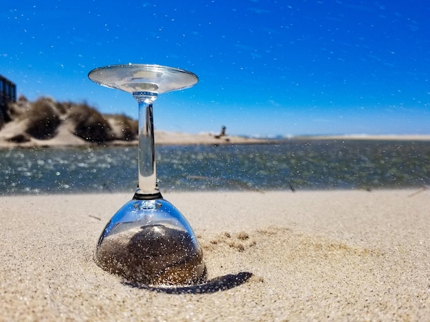 Nahaufnahme von Glas am Strand vor klarem blauen Himmel