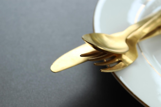 Nahaufnahme von goldenen Essgeräten auf einem Teller auf dem Tisch