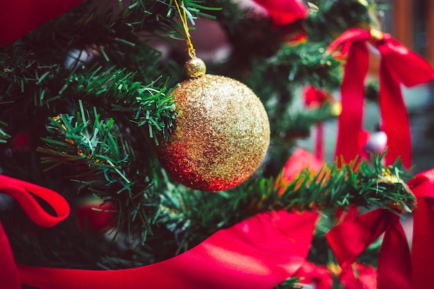 Nahaufnahme von Goldkugeln und rotem Band am Weihnachtsbaum Weihnachtshintergrund