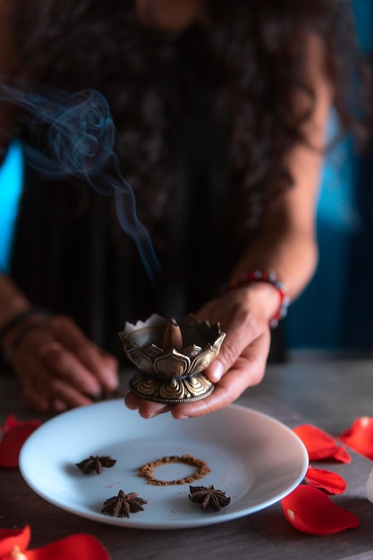 Foto nahaufnahme von händen, die am tag der toten eine weihrauchhexe anzünden und ein reinigungsritual durchführen. halloween, spiritueller glaube, weiße magie