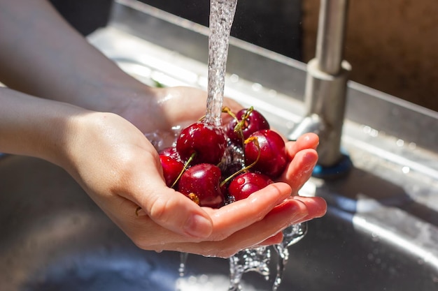 Nahaufnahme von Händen, die Beeren unter Wasser waschen