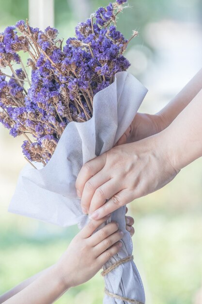 Foto nahaufnahme von händen, die einen lila bouquet halten