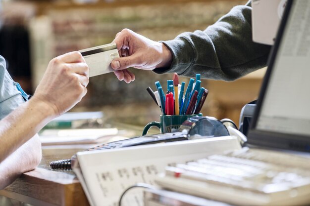 Nahaufnahme von Händen, die während eines Einzelhandelsverkaufs eine Kreditkarte austauschen