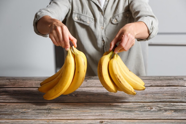 Nahaufnahme von Händen, die zwei Bananenzweige halten. Gesunder Lebensstil und Ernährungskonzept