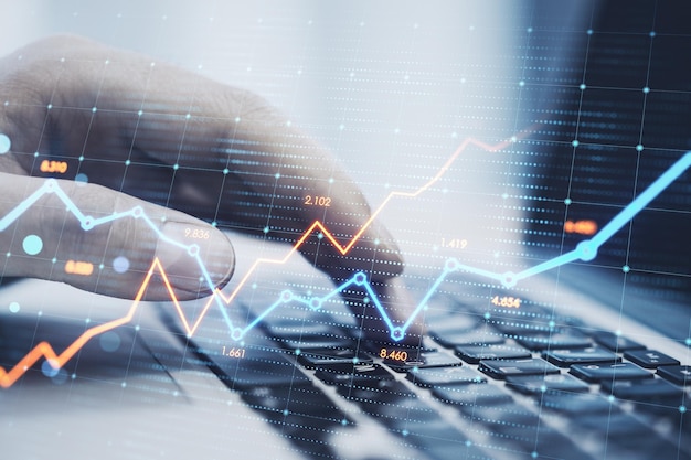 Nahaufnahme von Hand mit Laptop-Tastatur mit leuchtenden Business-Diagramm auf verschwommenem Hintergrund Aktienwachstum und Finanzdiagrammkonzept Doppelbelichtung