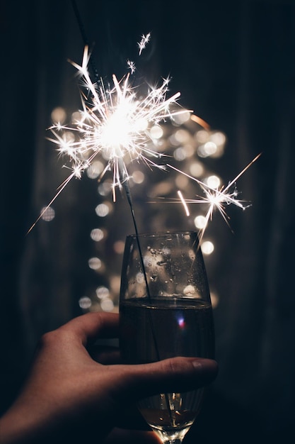 Nahaufnahme von Handchampagnerflöte und Funkel in der Nacht